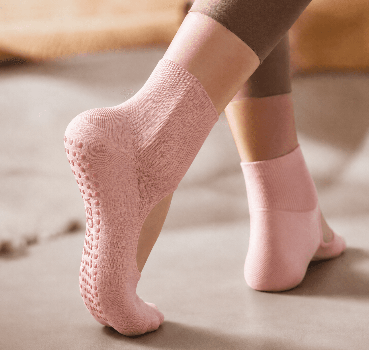 Pink custom Pilates grip socks worn during studio movement