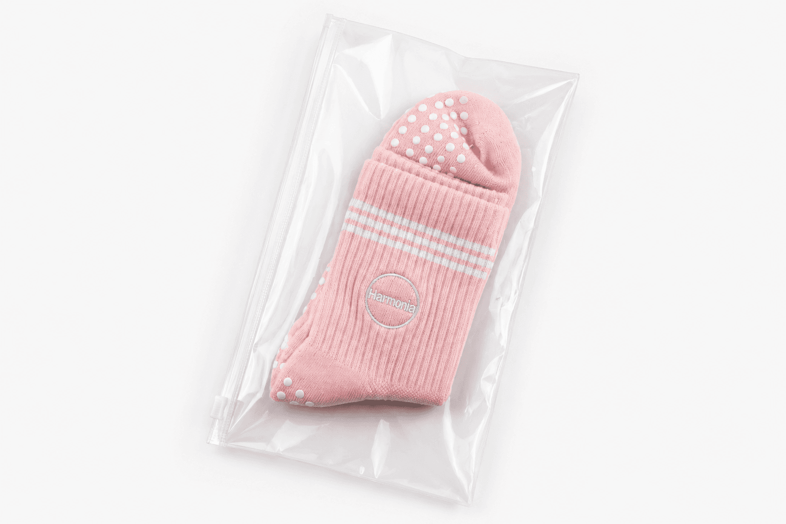 Pink custom Pilates grip sock with embroidered studio logo in a clear retail bag