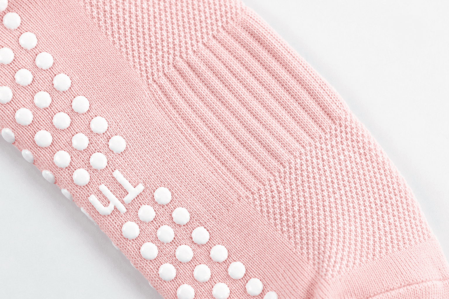 Close-up of custom silicone initials and grip dots on a pink Pilates sock
