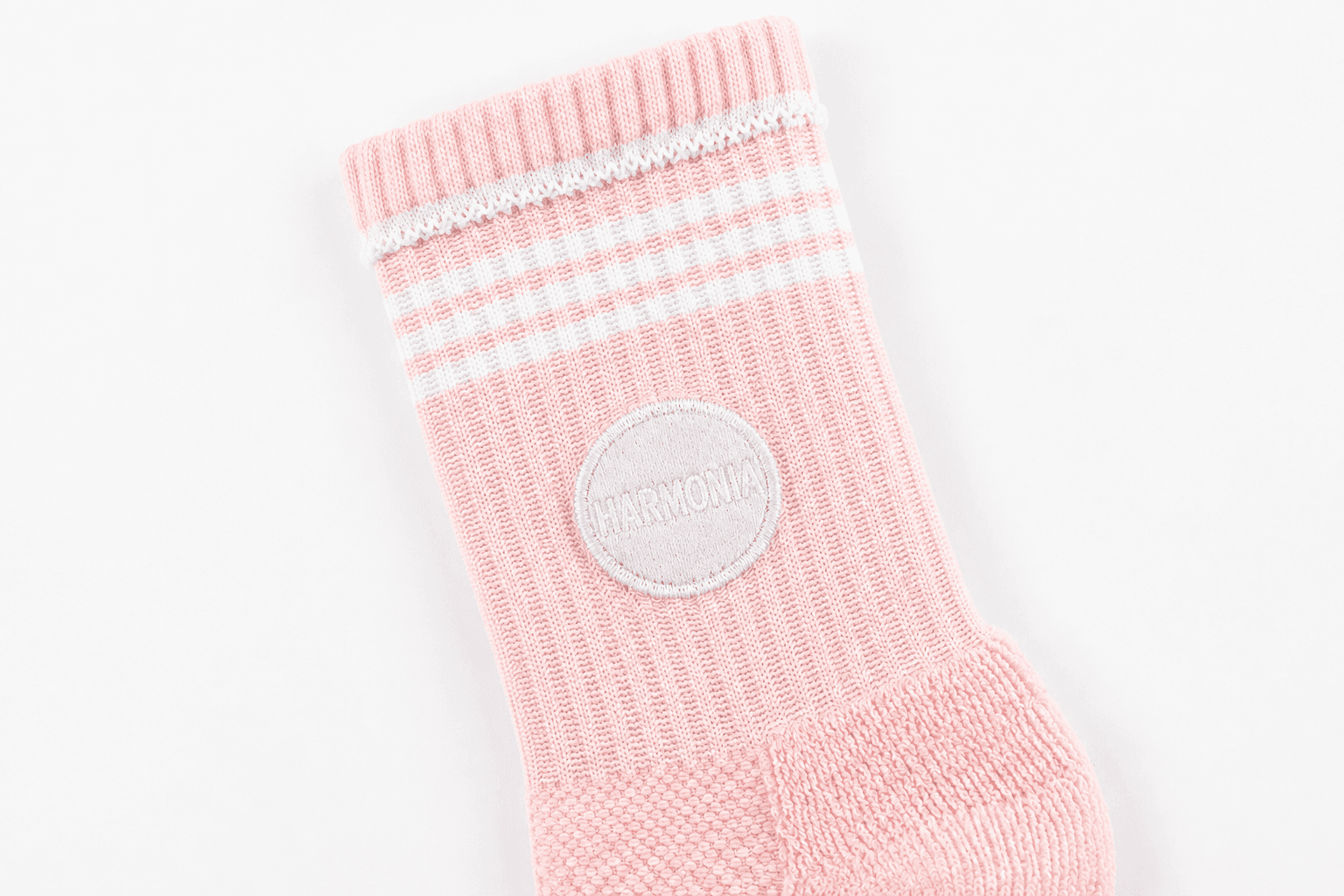 Embroidered circular studio logo on the cuff of a pink Pilates grip sock