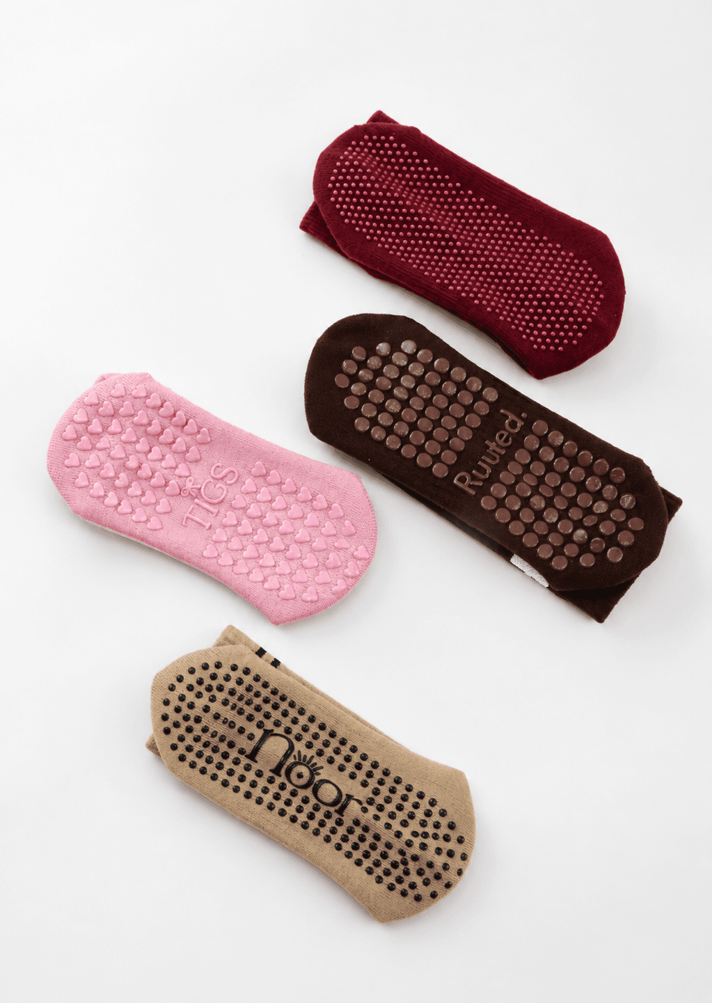 Four Pilates sock sole designs with dot, heart and logo-led grip layouts