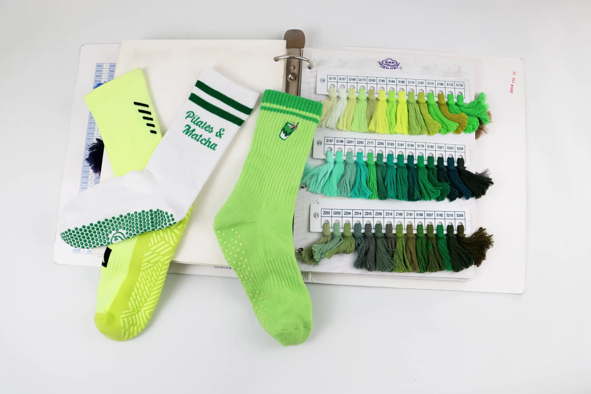 Grip socks displayed with green yarn swatches for material selection