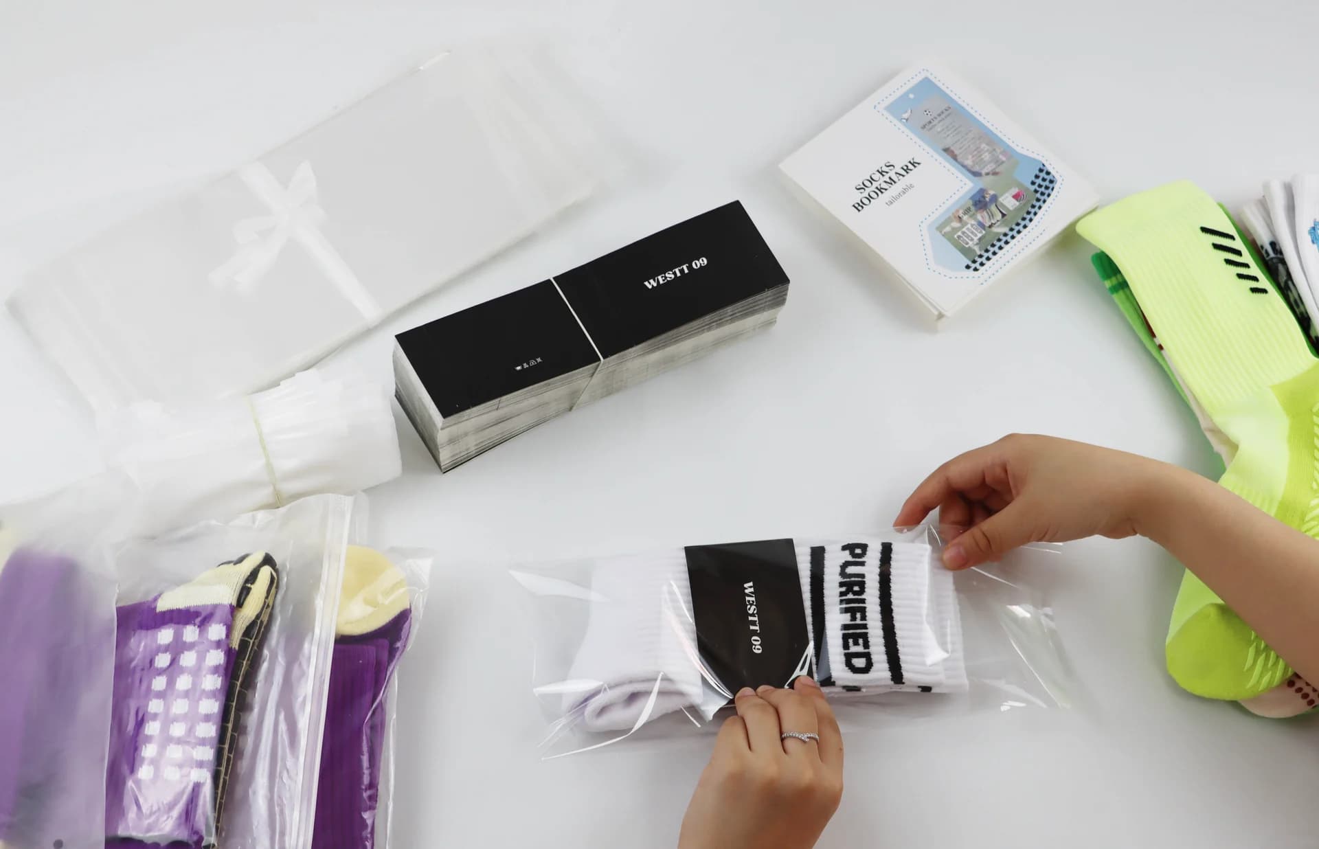 Private label sock being placed into a clear retail bag with branded card